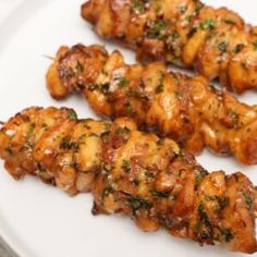 two skewers of chicken on a white plate