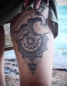 a woman's leg with a tattoo on it and an ocean in the background