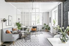 a living room filled with furniture and lots of plants on top of a hard wood floor