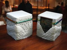 two white ceramic containers sitting on top of a wooden table