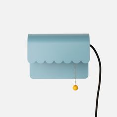 a blue lamp with a yellow ball hanging from it's side on a black cord