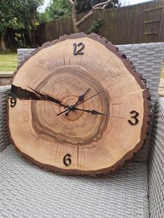 a clock that is sitting on top of a chair in the grass near a fence