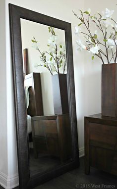 a large mirror sitting on top of a wooden dresser next to a vase filled with flowers