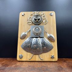 a decorative metal object on top of a wooden table next to a black wall and wood floor