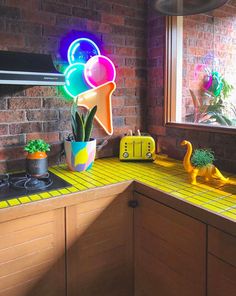 a kitchen counter topped with a potted plant next to a neon sign that says ice cream