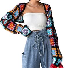 a woman wearing blue jeans and a white crop top with colorful crocheted sleeves