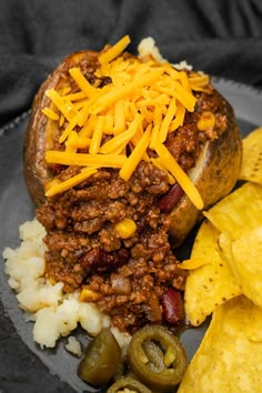 a chili cheese stuffed potato on a plate with chips