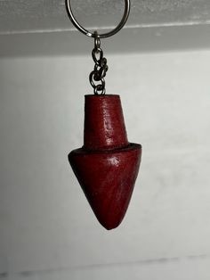 a red wooden object hanging from a metal hook on a chain with a ring around it