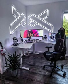 a desk with two computer monitors on it and a plant in front of the monitor