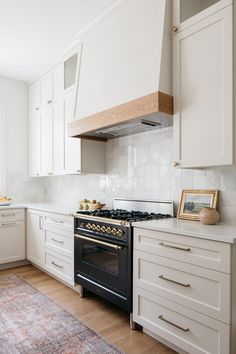 a stove top oven sitting inside of a kitchen next to white cupboards and drawers