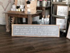 a wooden sign sitting on top of a hard wood floor next to a chair and table