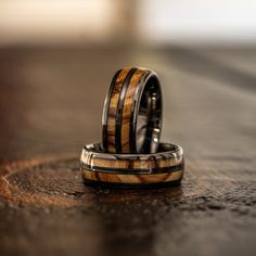 two wedding rings with wood inlays sitting on a table