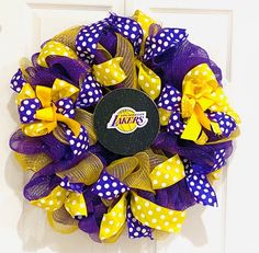 a purple and yellow wreath with the los angeles lakers logo is hanging on a door