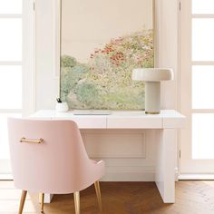 a white desk with a pink chair in front of it and a painting on the wall