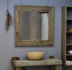 a bowl is sitting on a table in front of a mirror and shelving unit