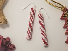 two red and white beaded earrings sitting on top of a table next to other items