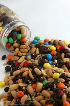 a jar filled with lots of candy and nuts next to a pile of cereals