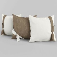 three brown and white pillows with ties on them, one in the shape of a bow