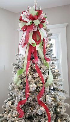 a white christmas tree with red and green ribbons