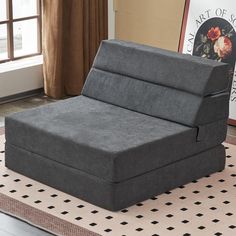 a gray couch sitting on top of a rug next to a window