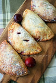 three pastries on a cutting board with cherries