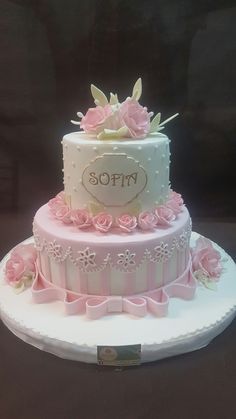 a three tiered cake with pink flowers on the top and white icing, sitting on a plate