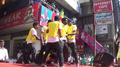 men in yellow shirts and black pants are dancing on the street while people look on