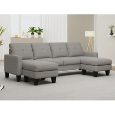 a grey sectional couch sitting on top of a carpeted floor