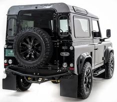 a black land rover is parked on a white surface with no one around it,