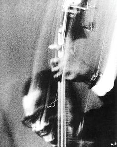 black and white photograph of a man playing the guitar with blurry image behind him