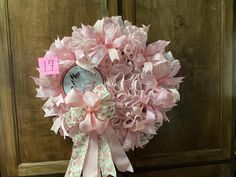 a bouquet of pink flowers on display in front of a wooden door with a name tag attached to it