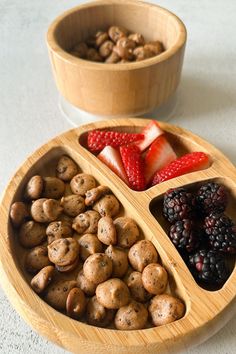 two wooden bowls filled with berries, nuts and strawberries on top of a table