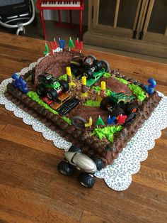 a birthday cake that is shaped like a train track with toy cars on the tracks