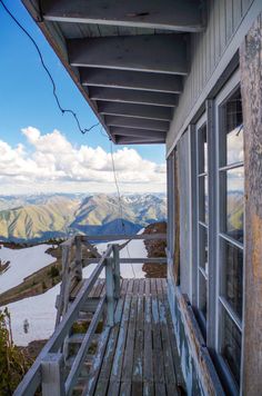 an old wooden porch overlooks the mountains and lake in the distance with snow on the ground