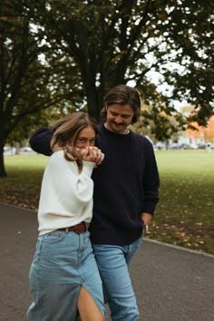 a man and woman are walking down the street with their arms around each other's shoulders