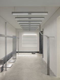 an empty white room with metal handrails and lights on the ceiling is lit by recessed lighting