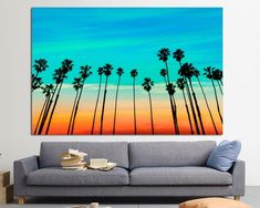 a living room with a couch and painting on the wall in front of palm trees