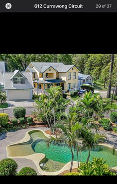 an aerial view of a house with a pool in the foreground and palm trees surrounding it