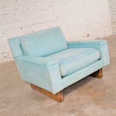 a light blue chair sitting in front of a brick wall with white bricks on it