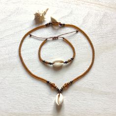 Jewelry made of natural cowrie shells (16 - 19 mm), honey / bronze color original Czech glass beads (3.1 / 4.1 / 5.6 mm Rocailles Preciosa) and waxed polyester cord (original Linhasita 1 mm). A necklace is available in 3 lengths (40 cm = 15.74 inches, 45 cm = 17.71 inches or 50 cm = 19.68 inches). The length of a bracelet is adjustable and should fit all wrists sizes.     The jewelry is robust and fully waterproof. If you have any questions/wishes, please don't hesitate to contact me! Bohemian Gold Beaded Bracelets With Shell, Bohemian Gold Beaded Shell Bracelets, Gold Bohemian Strand Beaded Bracelets, Adjustable Gold Beaded Shell Necklace, Bohemian Amber Jewelry For Beach, Gold Bohemian Shell For Festival, Handmade Gold Bohemian Shell, Handmade Bohemian Gold Shell, Bohemian Brown Shell As Gift