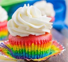 two cupcakes with white frosting and rainbow icing on the top one