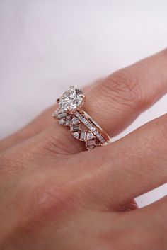 a woman's hand with a diamond ring on top of her finger and an engagement band