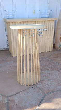 a wooden table sitting on top of a stone floor next to a white garage door