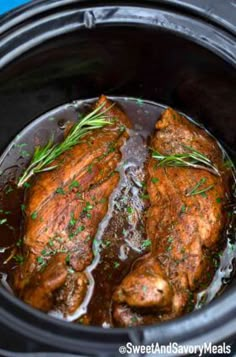 two pieces of meat in a slow cooker with some herbs on the top of it