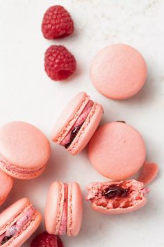 pink macaroons and raspberries on a white surface