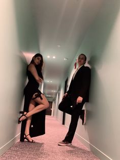 a man and woman dressed in business attire posing for a photo while leaning against a wall