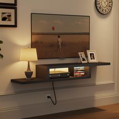 a flat screen tv sitting on top of a wooden shelf next to a wall mounted clock