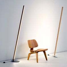 two wooden chairs sitting next to each other in front of a white wall and floor