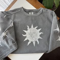 Hand carved linoleum design of sun and moon with stars that is hand stamped onto a comfy sweatshirt. Since sweatshirts are stamped by hand there will be variations in placement and intensity of ink. Each print is unique!  Current sizes available are S-XL. Sweatshirt have a relaxed fit. I recommend sizing up if you want a more oversized look. Turn around time is 5-7 days to give the oil-based ink time to fully dry. I recommend laundering before wearing. Fading can occur if not properly cared for Bohemian Cotton Tops With Sun And Moon Design, Sun And Moon Bleach Shirt, Sun And Moon Shirt Design, Cotton Crew Neck Tops With Sun And Moon Design, Cotton Tops With Sun And Moon Design, Relaxed Fit, Casual Sun And Moon Design Short Sleeve T-shirt, Bohemian Cotton T-shirt With Sun And Moon Design, Celestial Moon Print Crew Neck T-shirt, Trendy Crewneck