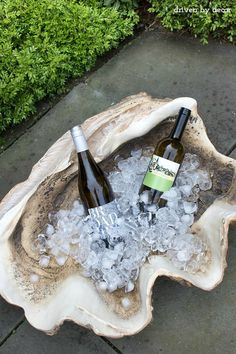 two bottles of wine sitting on top of ice in a bowl with some water inside